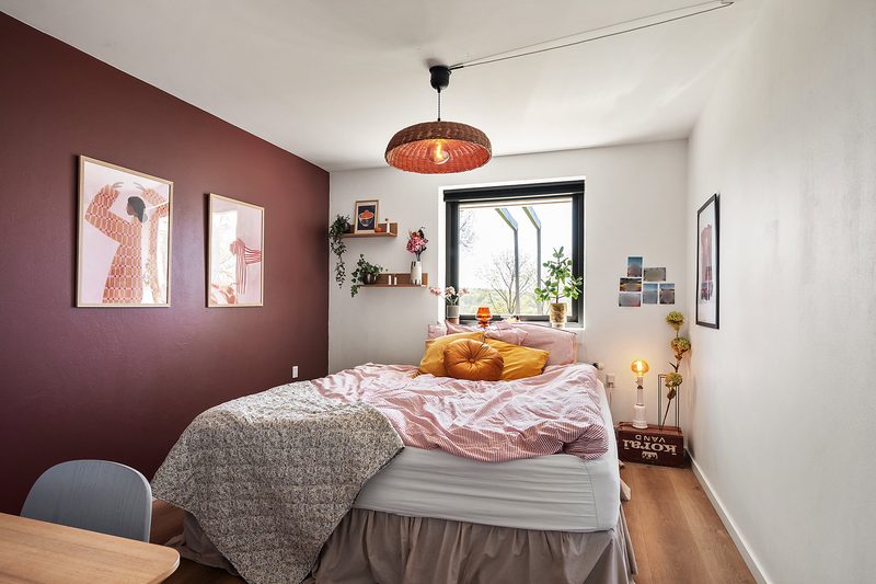 Schlafzimmer mit Doppelbett und roter Wand