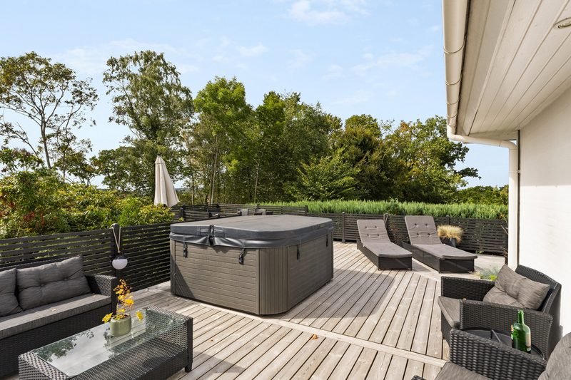 Holzterrasse mit Außenwhirlpool und Loungemöbeln